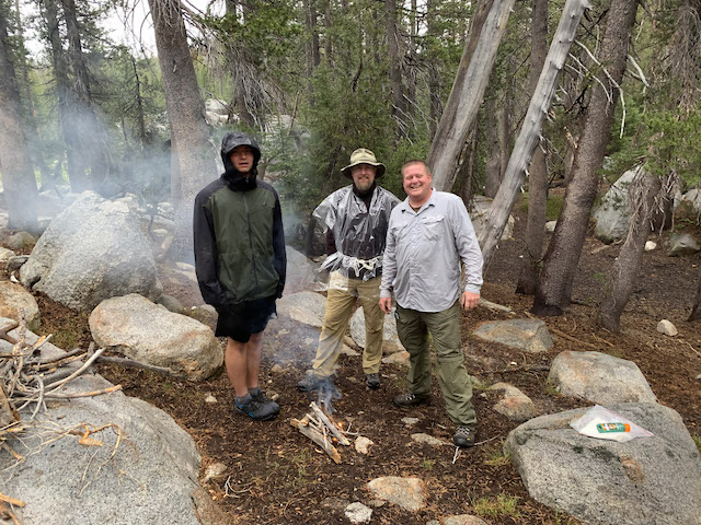 Andrew, James, and Kissner around fire at camp. ©2021 David Rogers